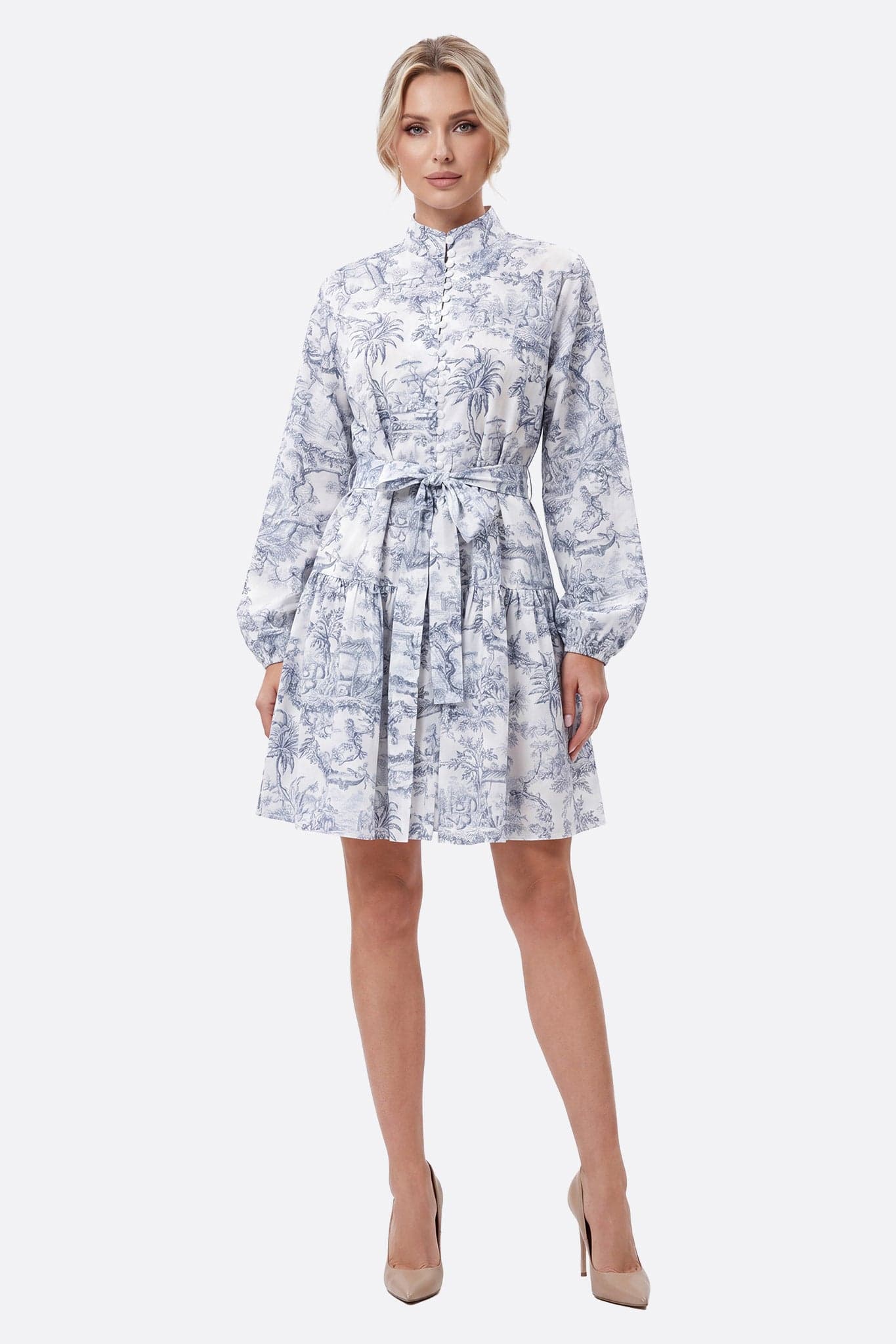 Mannequin de face portant une robe courte imprimé toile de Jouy à taille ceinturée, col montant et boutons