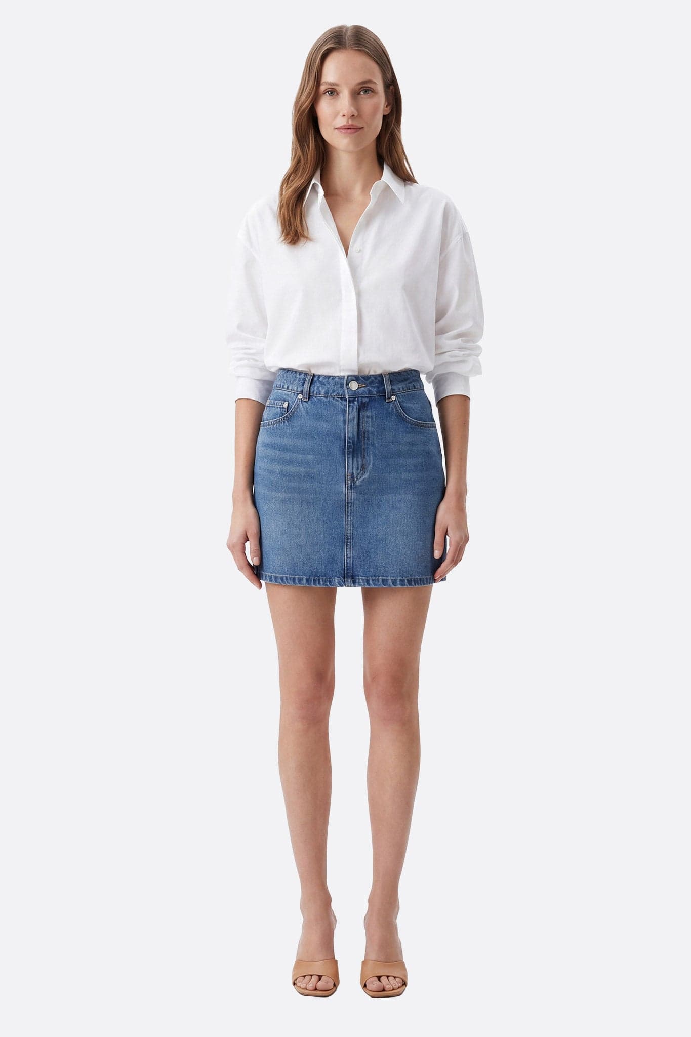 Mannequin de face portant une jupe courte denim en coton coupe droite, taille haute et poches visibles