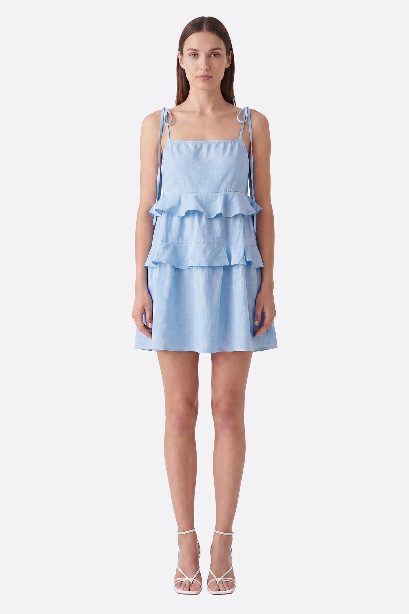 Model von vorne in einem hellblauen kurzen Kleid mit Volants und gebundenen Trägern, leichte Textur