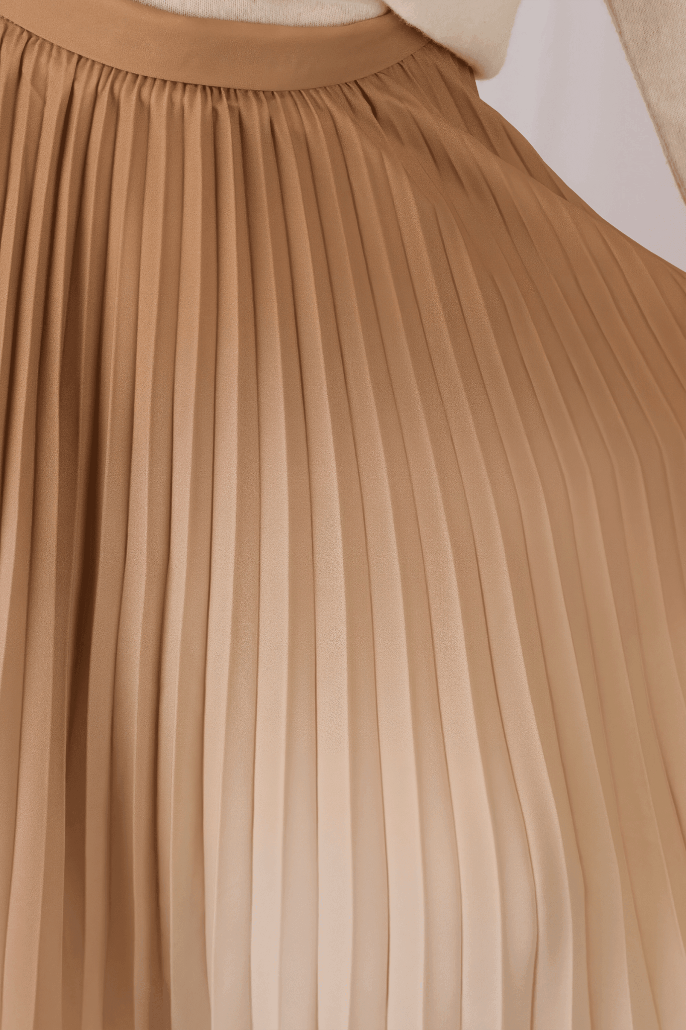 Vue détaillée de la jupe plissée longue beige, mettant en avant le dégradé délicat et son allure raffinée pour un style...