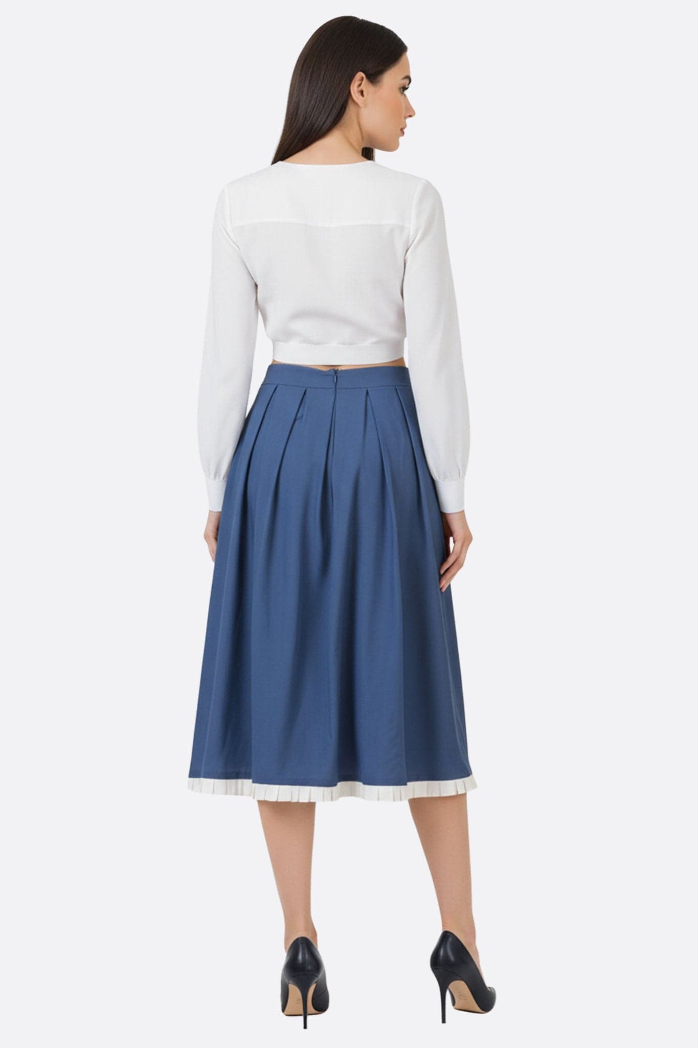 Détail de la jupe midi plissée bleu nuit, soulignée par un bord écru, idéale pour une tenue raffinée au quotidien.