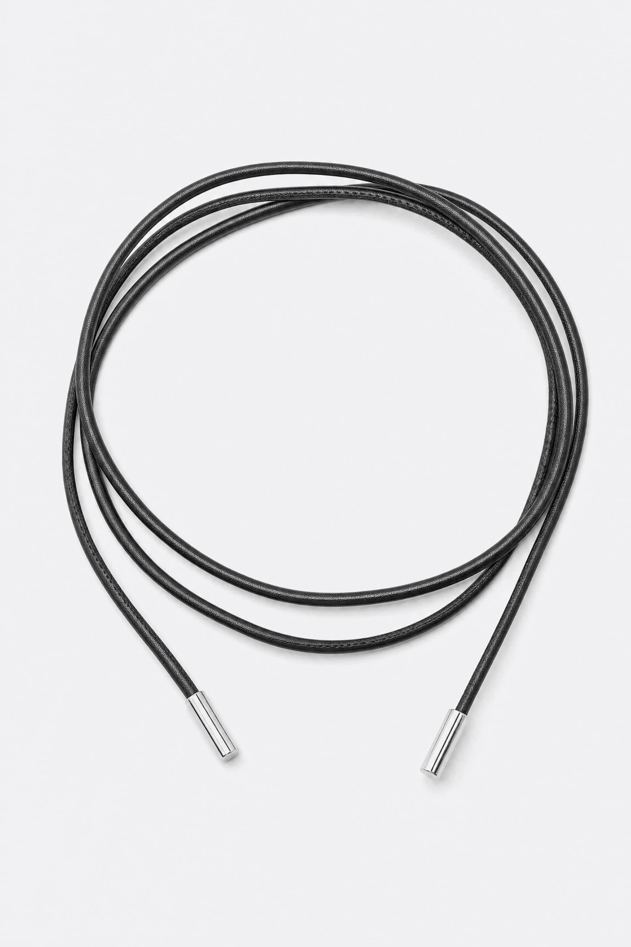 Ceinture cordon noire fine à embouts métalliques argentés, posée en boucles souples