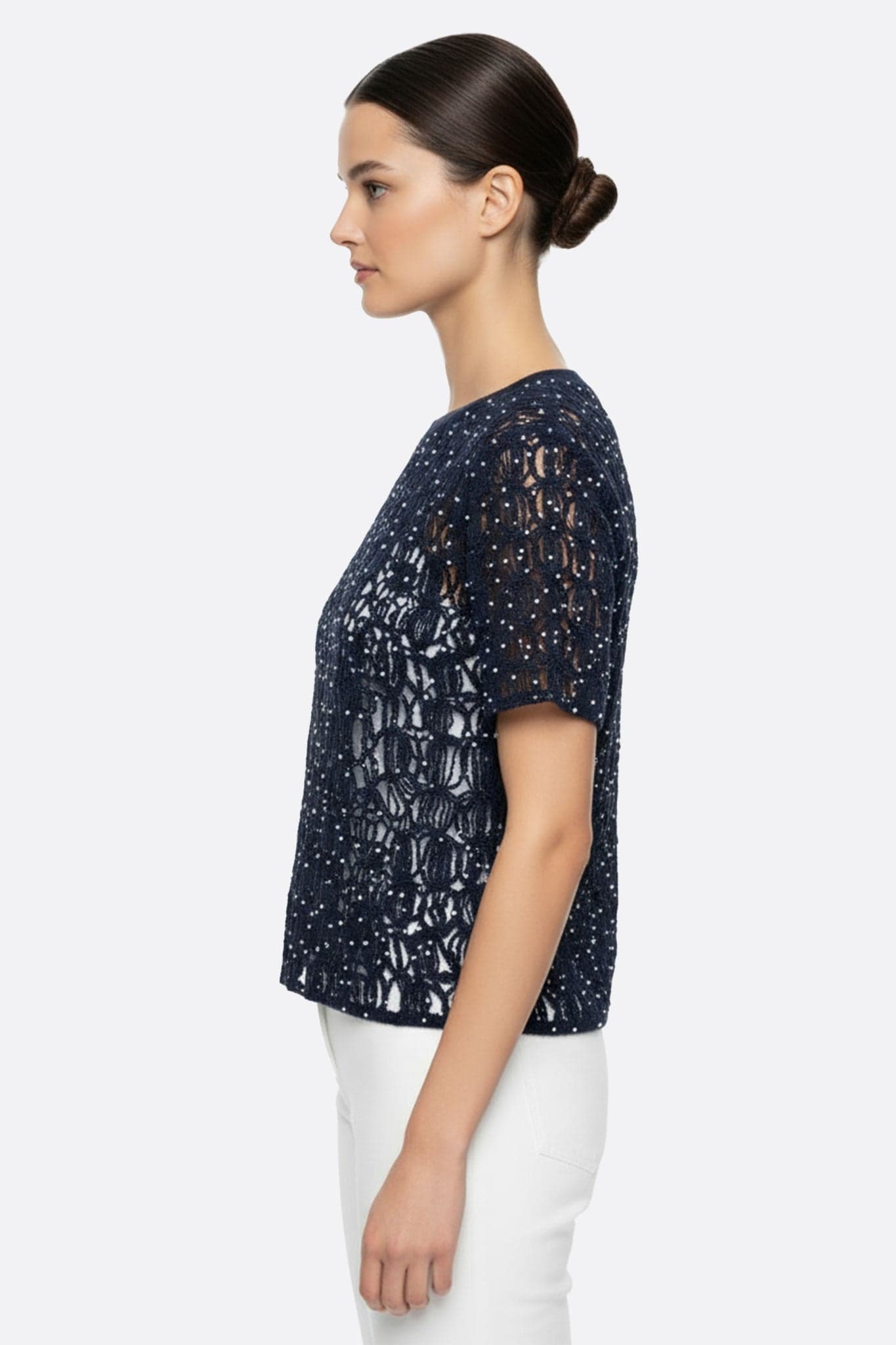 Nahaufnahme des marineblauen Lochmuster-Pullovers aus Mohair mit Lurex-Glanz, der seine kurzen Ärmel und zarte Textur zeigt.