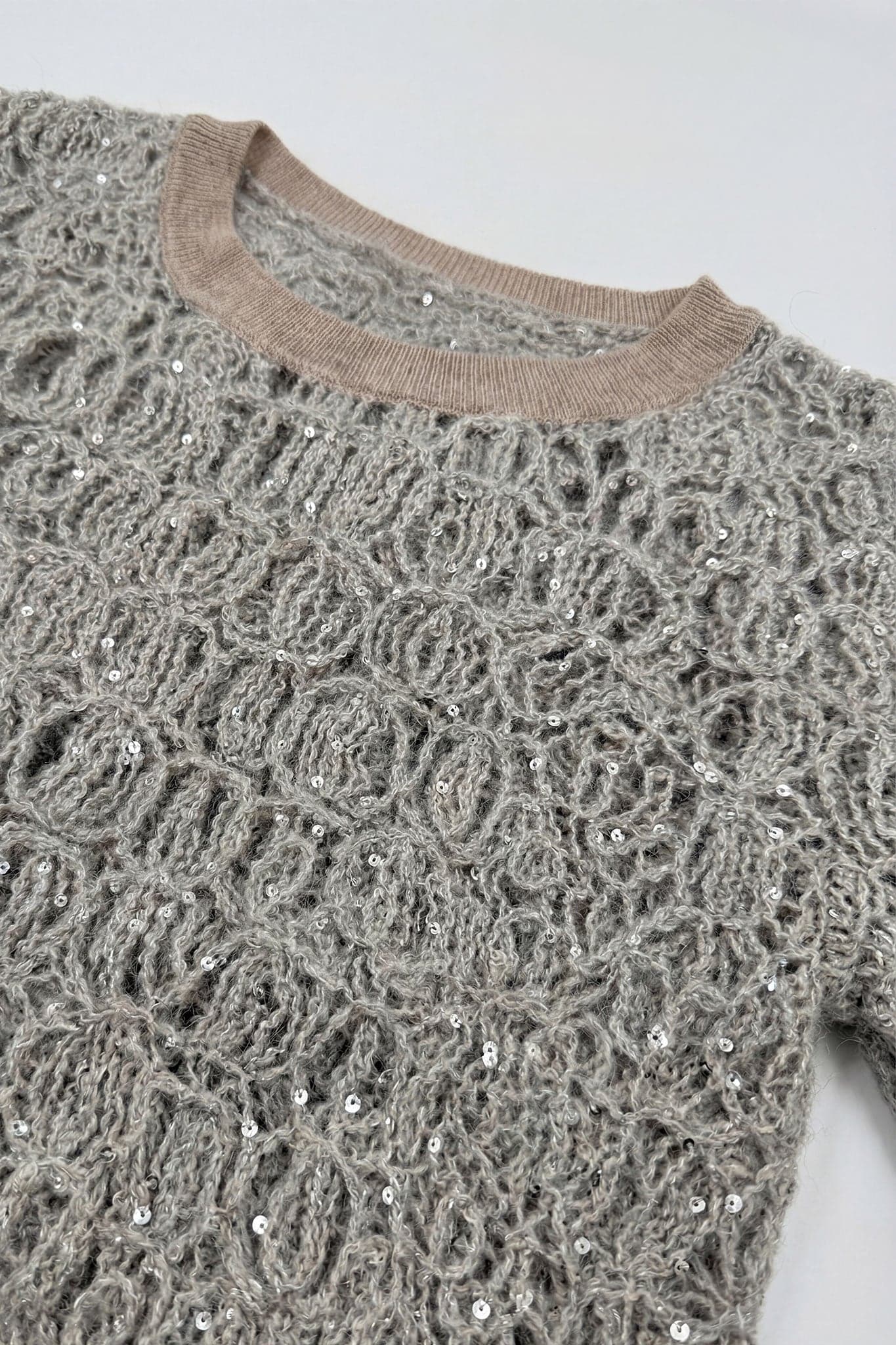 Dettagli raffinati del pull traforato grigio perla in maglia di mohair e lurex, ideale per aggiungere un tocco raffinato al tuo stile.