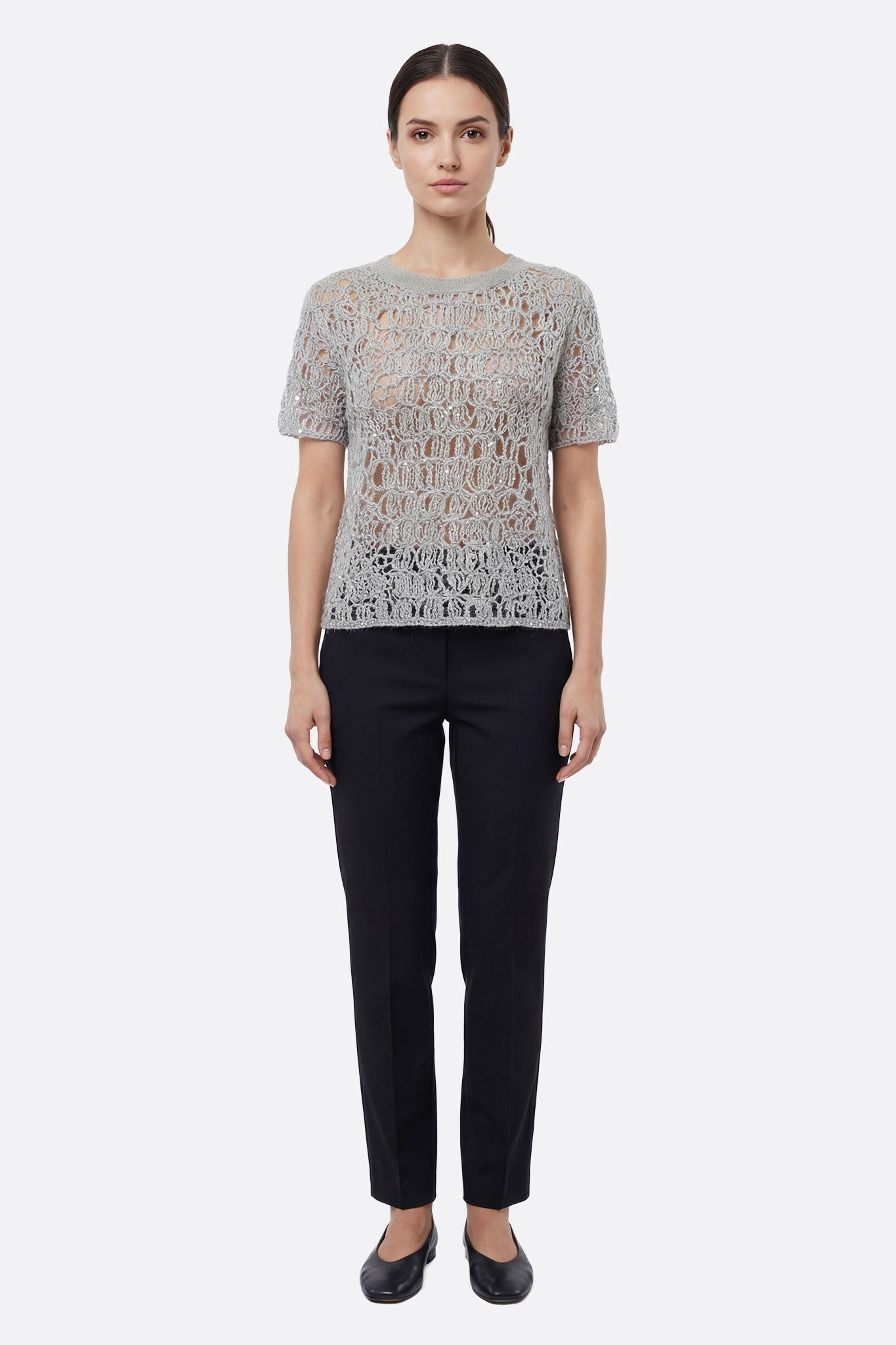 Detalle cautivador del jersey de punto calado gris perla con lurex, una pieza chic para realzar un look veraniego.