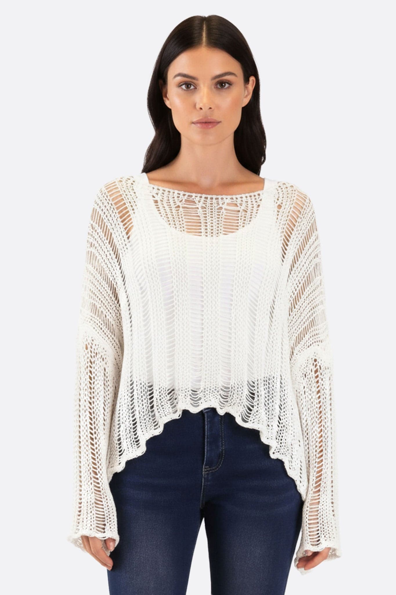 Pull en maille ajourée blanche, chic et léger, parfait pour des tenues estivales élégantes, porté avec style.
