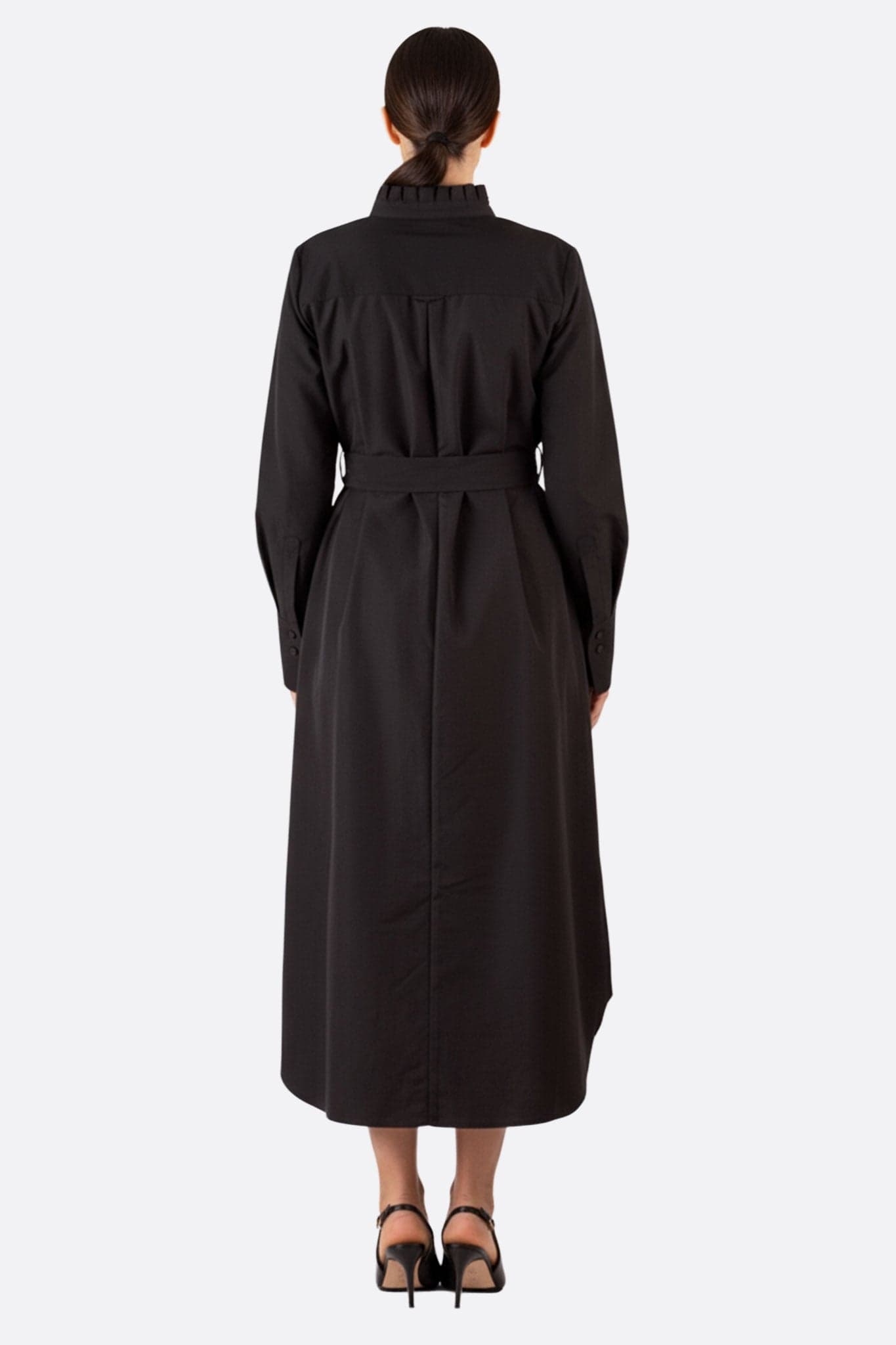 Dreiviertelansicht des langen schwarzen Gürtel-Hemdkleides, die die elegante Silhouette und den zeitgenössischen Stil hervorhebt.