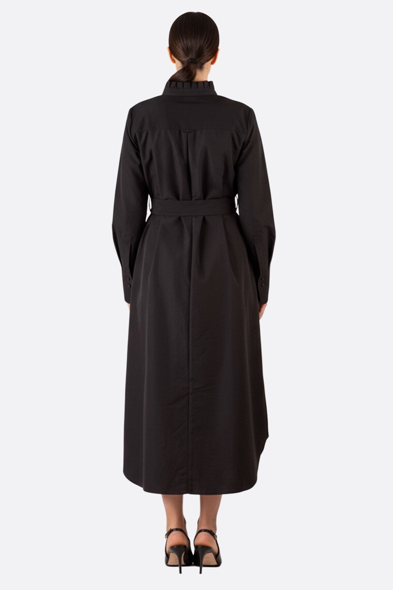 Dreiviertelansicht des langen schwarzen Gürtel-Hemdkleides, die die elegante Silhouette und den zeitgenössischen Stil hervorhebt.