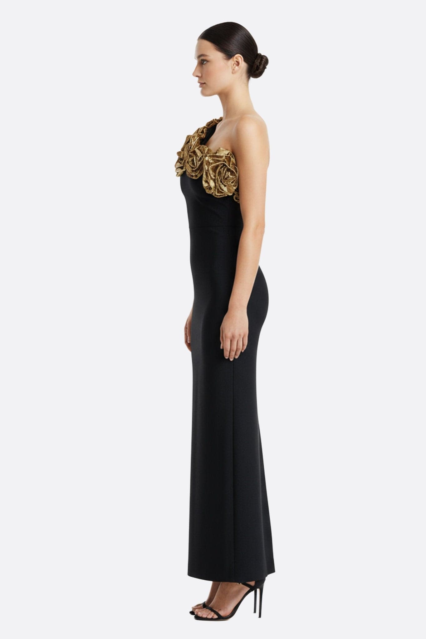 Detail of the black dress with asymmetric neckline, highlighting its golden flowers for a chic and refined look.