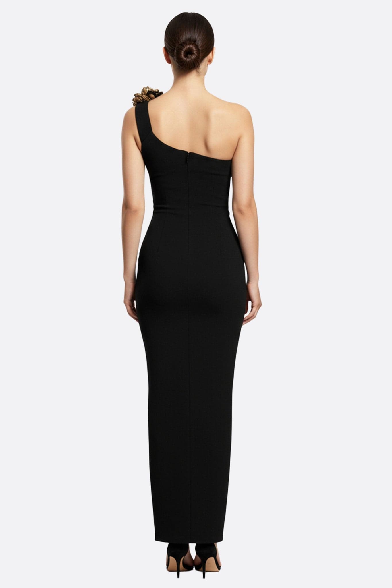 Details of the long black dress with asymmetric neckline, showcasing the golden floral motifs for a glamorous look.