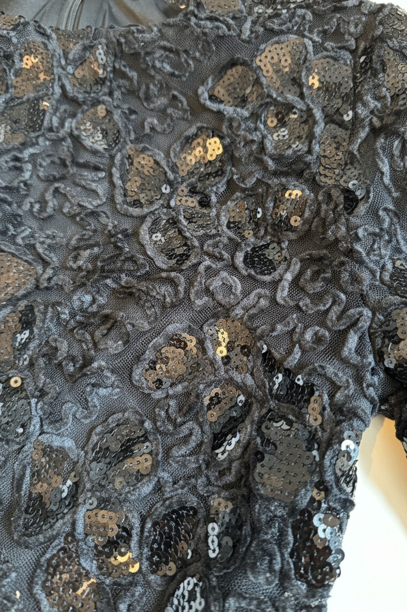 Texte délicat de la dentelle noire et éclat des sequins sur les manches longues de cette robe, idéale pour des occasions...