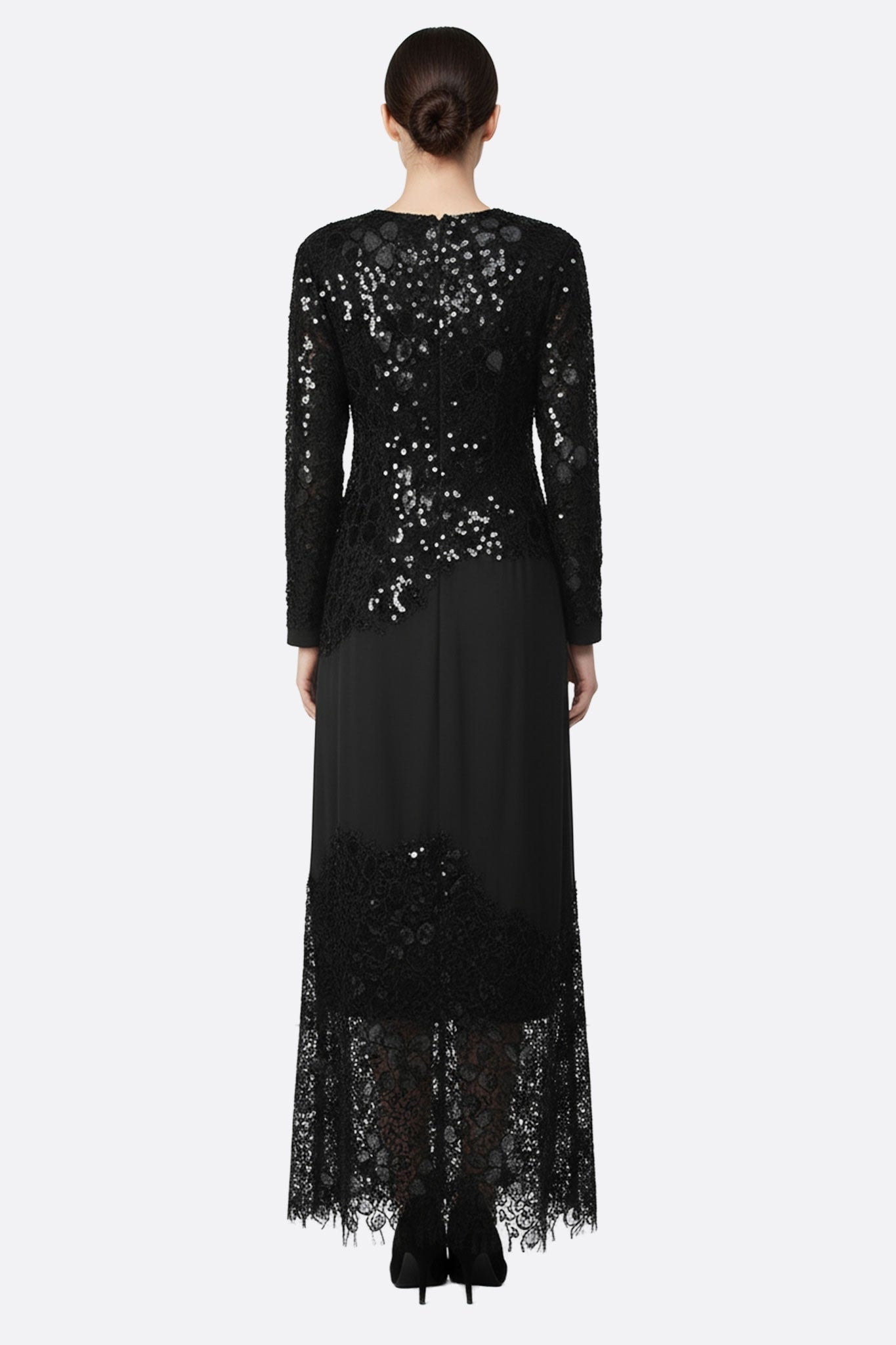 Robe longue noire en dentelle et sequins, vue rapprochée mettant en avant les manches longues et la fluidité du tissu.