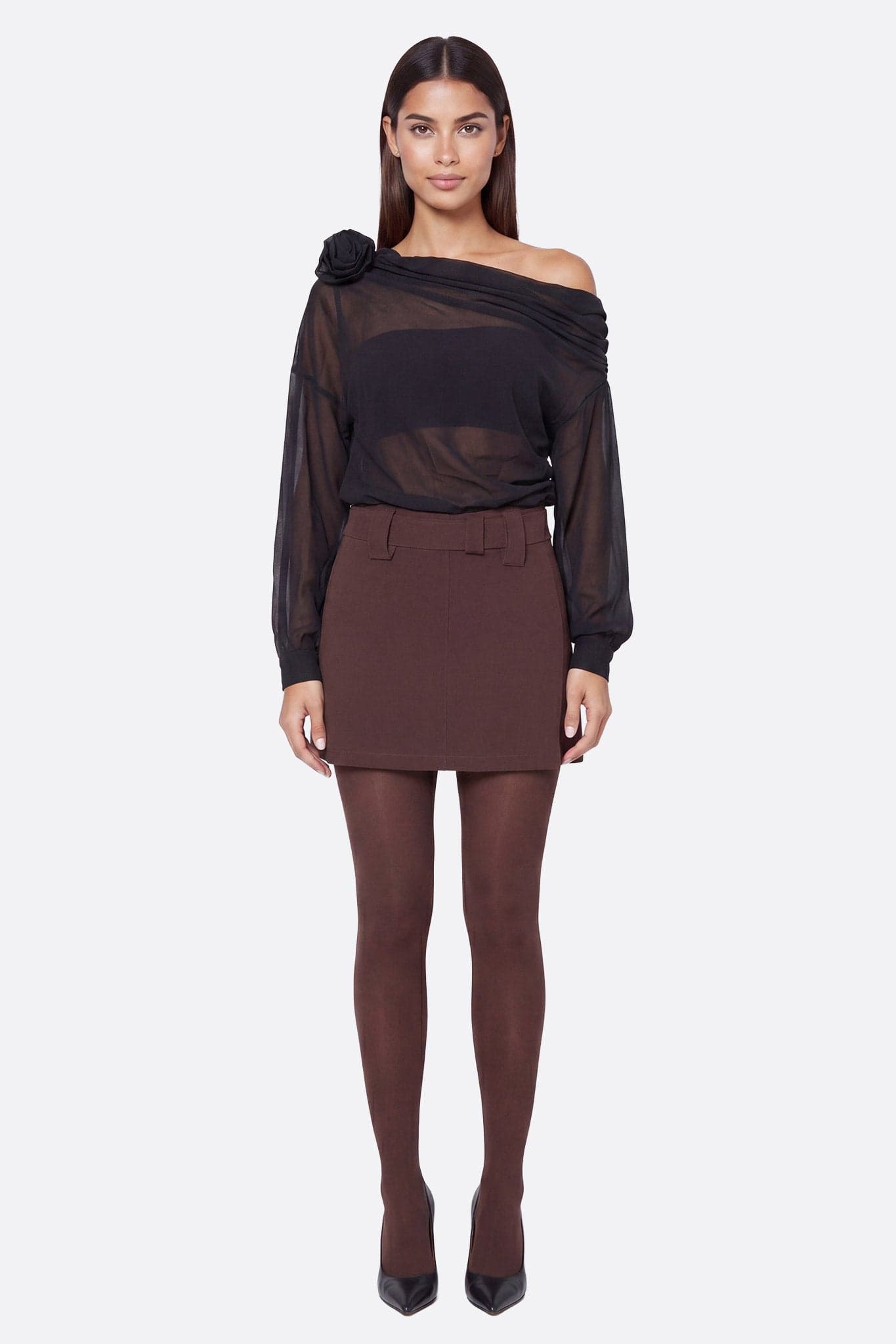 Mannequin de face portant un top asymétrique noir drapé à fleur sculptée sur l'épaule gauche