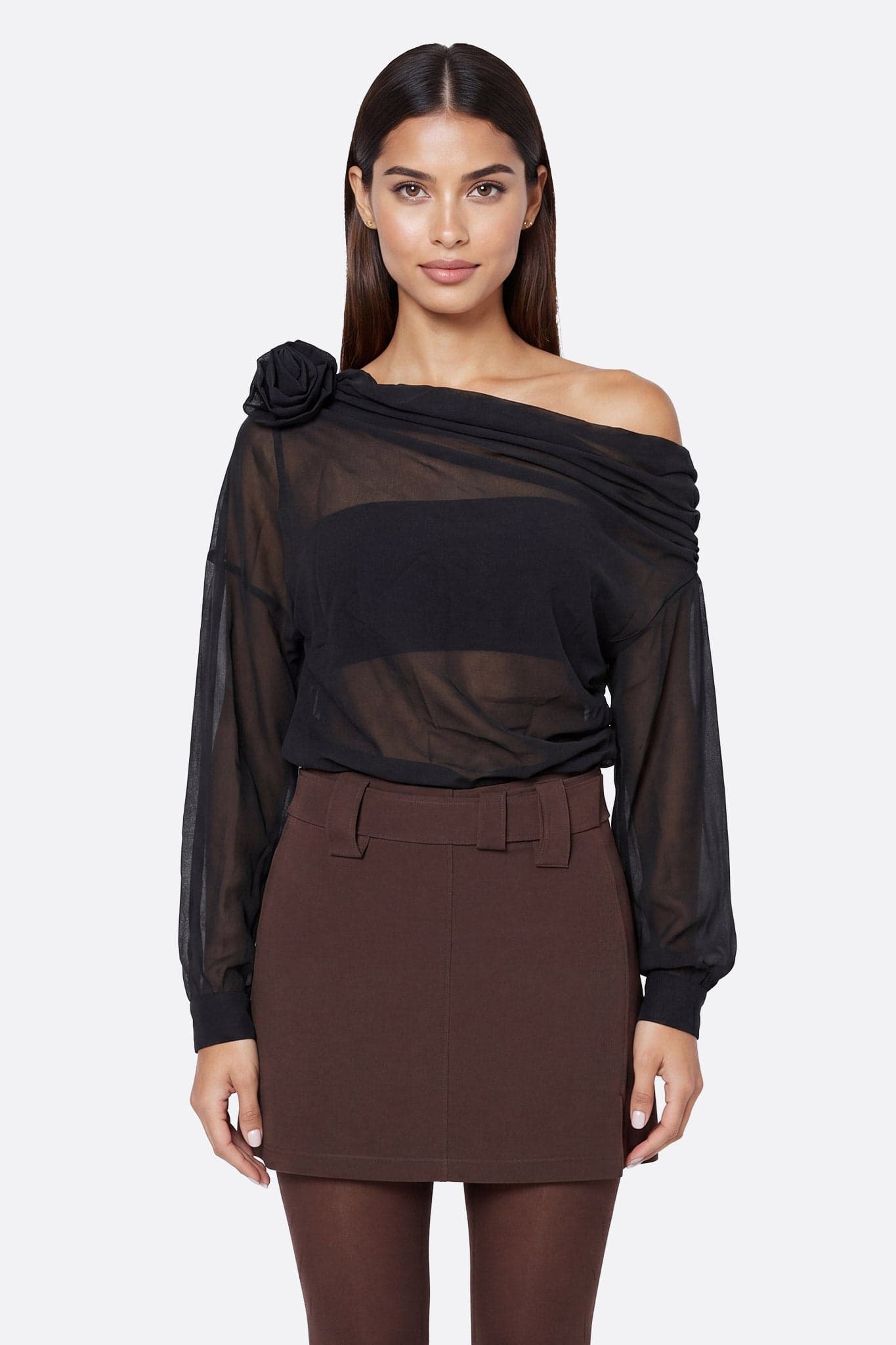 Mannequin de face portant un top asymétrique noir drapé en voile transparent avec fleur sculptée sur l'épaule