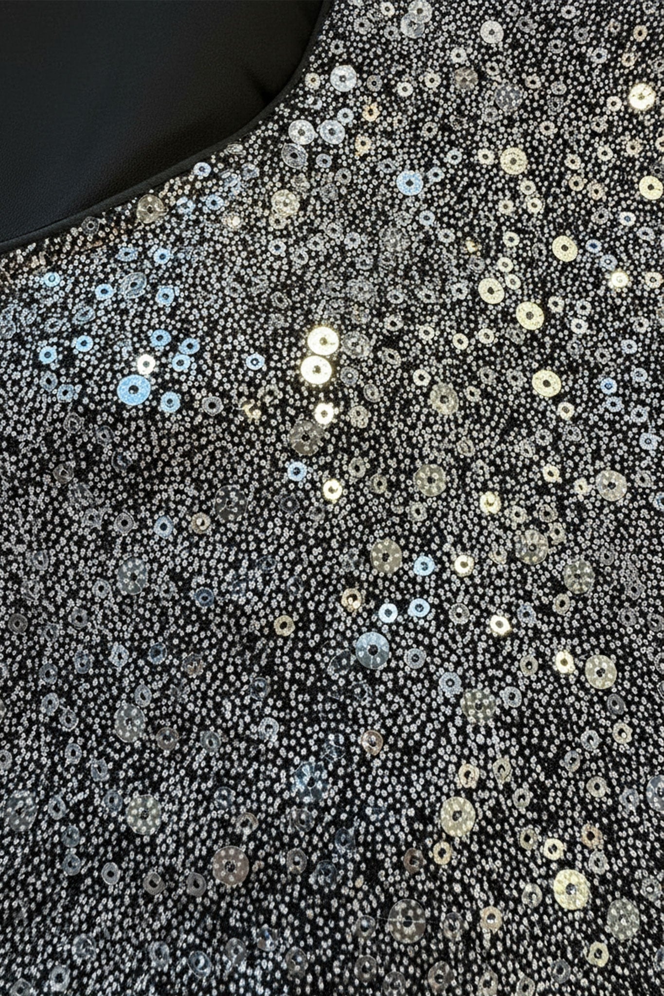 Top noir à sequins argent capturant la lumière, mise en valeur des poignets plissés, parfait pour une soirée élégante.