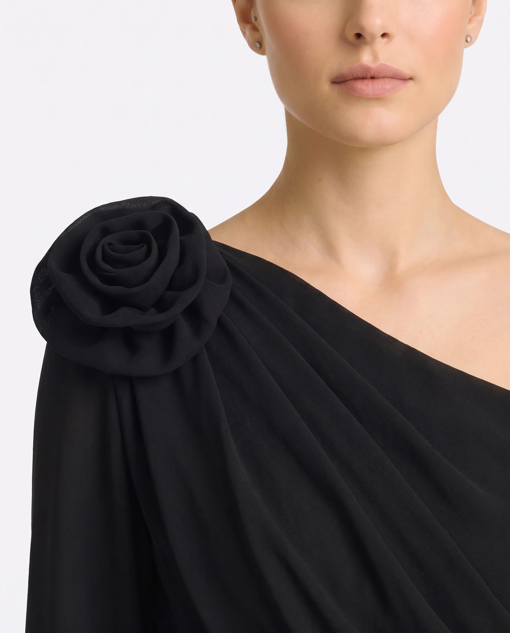 Gros plan sur la fleur sculptée en crêpe noir opaque et les fronces du drapé d'épaule